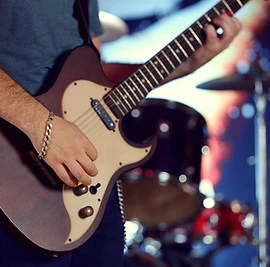 Young man playing on electric guitar close up.jpg