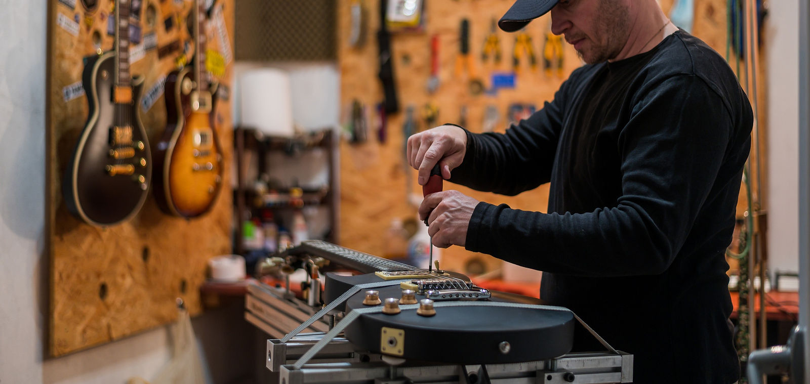 Black electrical guitar in repair service shop with a guitar luthier which fixes and tight