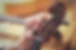 An old man (luthier) with aged hands is tuning a violin. You see other instruments like a
