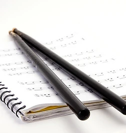 Two drumsticks on a book of notes.jpg