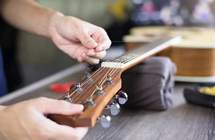 Acoustic guitar care, Craftsman is changing the strings, Close up..jpg